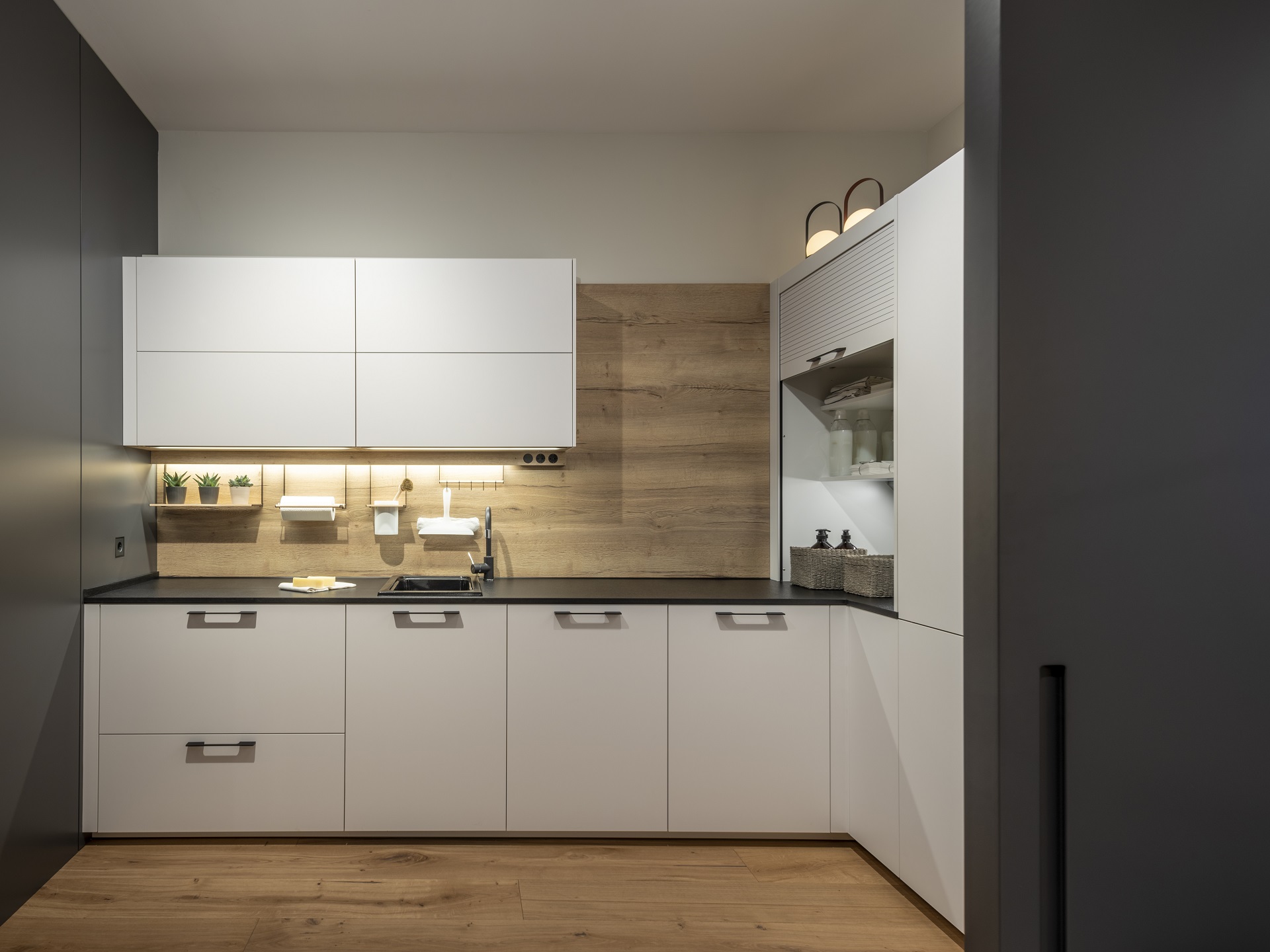 Parte del interior de una cocina moderna blanca con armarios con vidrio  esmerilado, una pared de ladrillo blanco y una encimera de madera. equipo  de cocina.